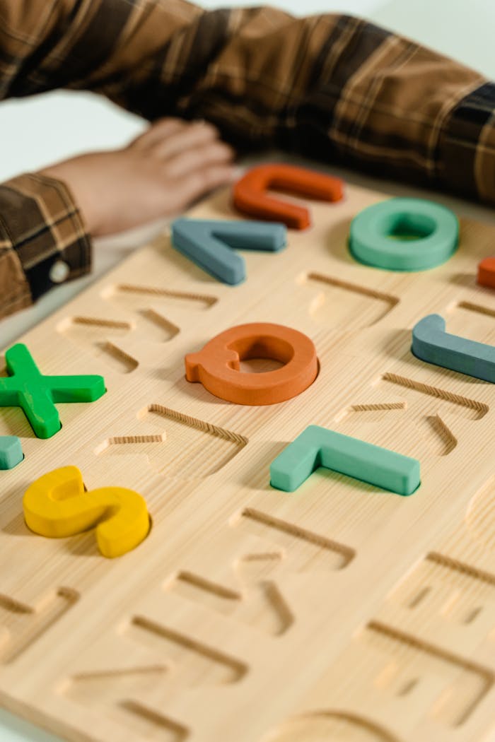 Colorful wooden letters puzzle with childs hands in focus, promoting fun learning.